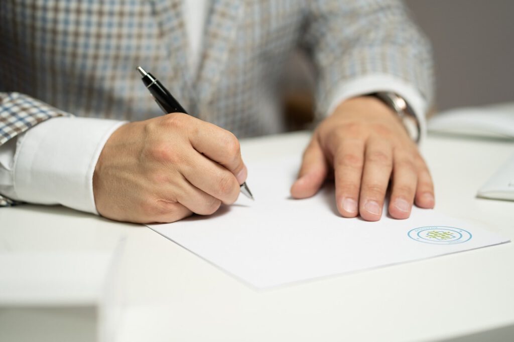 A swron translator signing on a paper sheet for his certified translations.