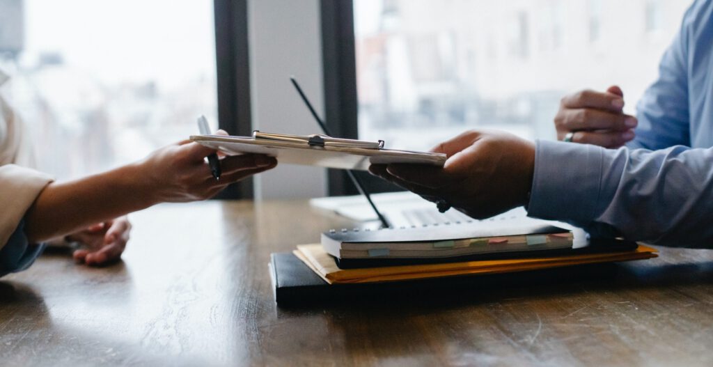 Two people exchanging documents in an office, illustrating HR field translations